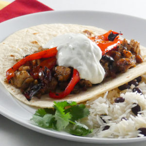 brown sugar lime chicken fajita with sour cream next to rice and beans